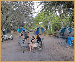 A tent is set up in a desert landscape, with the sun setting in the background. AI generated content