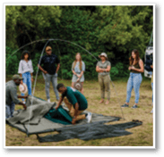 A group of people are standing next to their bicycles in a dirt lot. AI generated content