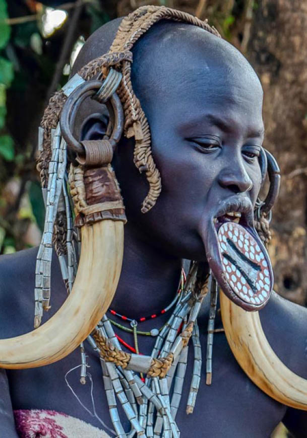 Ethiopia, a woman from the Mursi tribe with beautiful head decoration sits in front of her hut. Omo Valley, Jinka, 21th of february 2024 