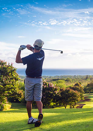 A man is swinging a golf club on a green course. Description generated by AI