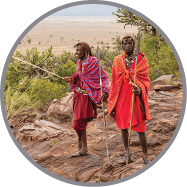 Two men standing on a rocky hill with red and orange clothing. Description generated by AI