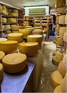 A room filled with yellow cheese, some stacked on shelves and others on a counter. AI generated content