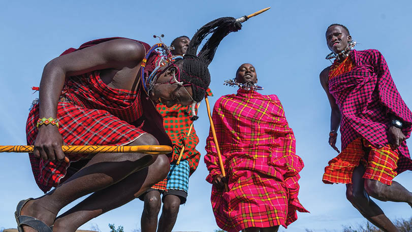 A group of people wearing colorful clothing and holding sticks. Description generated by AI