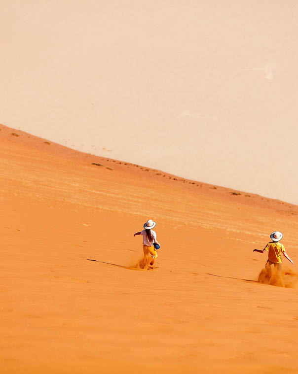 Kids brother and sister having fun running down famous red sand dune Big Daddy in Sossusvlei Namibia