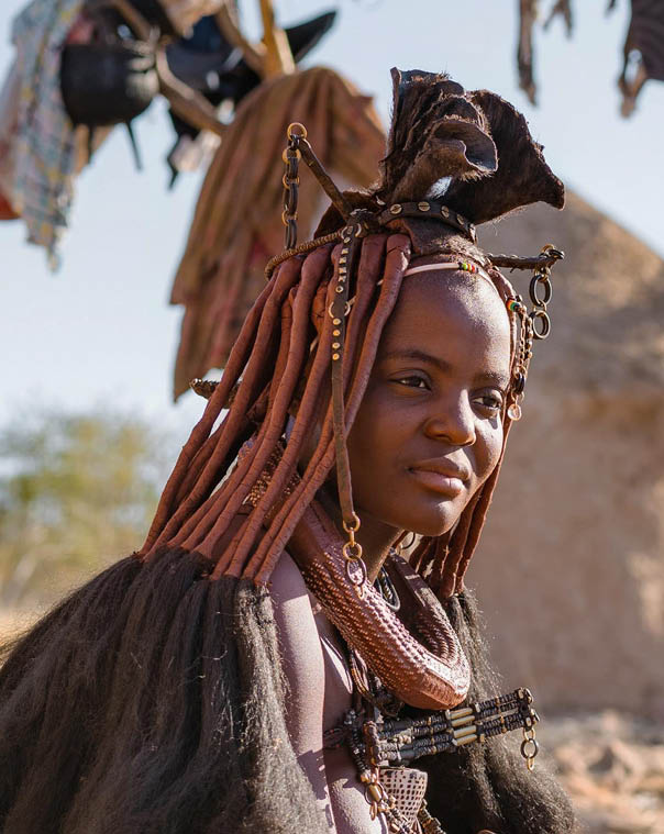 Panoramic shot showing Himba women sitting outside their huts in a traditional Himba village near Kamanjab in northern Namibia, Africa.