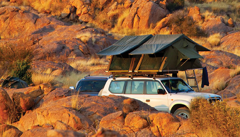 A white truck is parked in a rocky area with a tent in the background. AI generated content