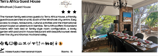 A large dining table is set up in a restaurant, with several chairs surrounding it. The table is adorned with plates, cups, and a wine glass. The restaurant is called Terra Africa Guest House and is located in Wynberg. AI generated content