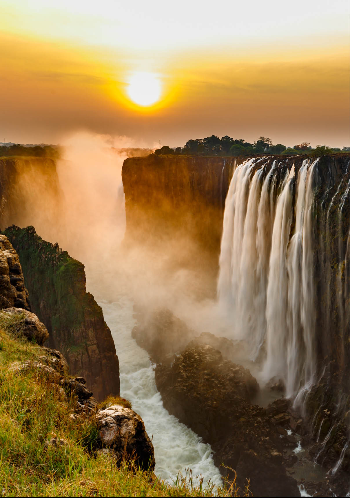 Victoria falls sunset with orange sun in the sky and tourist in view point