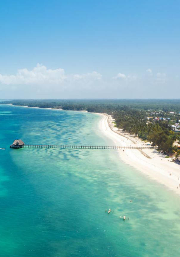 Aerial shot of Kiwengwa beach washed with turquoise Indian ocean waves. White sand sandbank beach on Zanzibar island, Tanzania. Exotic countries travel concept