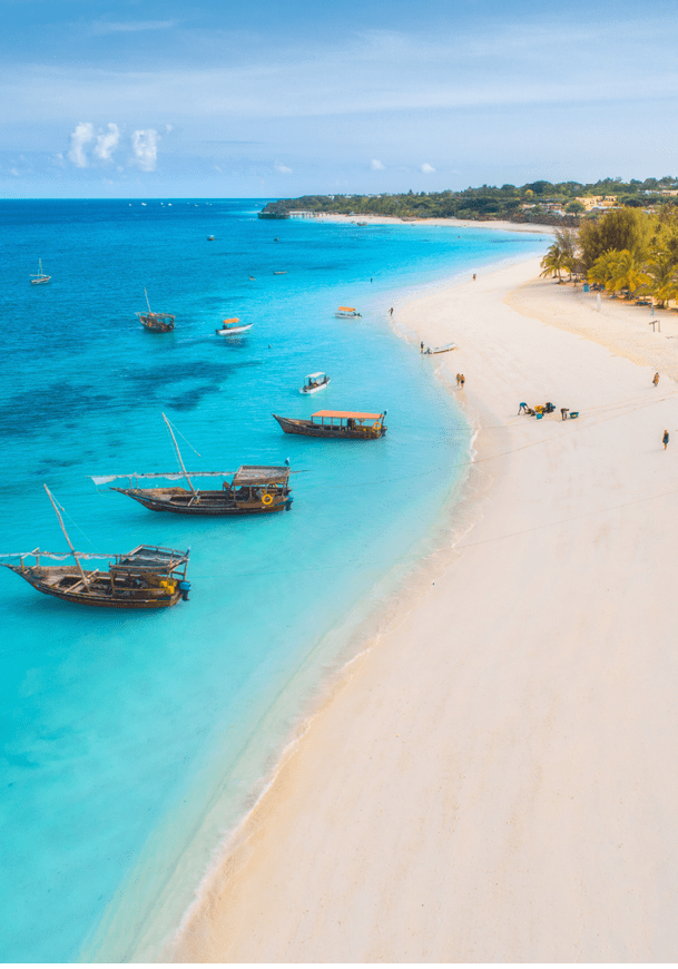 A beach with boats in the water and people on the sand. Description generated by AI