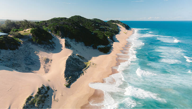 A beach scene with a sandy shore and a body of water. AI generated content